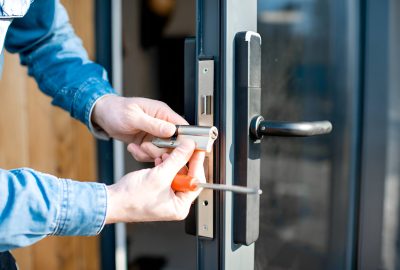 Close-up of a person installing a door lock cylinder using a screwdriver.