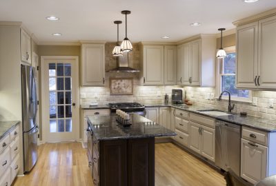 Kitchen with cream cabinets, dark granite countertops, a dark wood island, and stainless steel appliances.