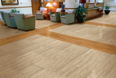 Waiting room with tan stone-look tile flooring accented by light wood borders, armchairs, and a reception desk.