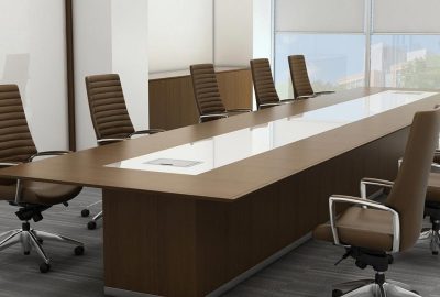 Modern conference room with a long brown wooden table and matching leather executive chairs.