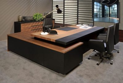 Luxury L-shaped office desk with dark wood and black finishes, paired with black leather executive chairs.