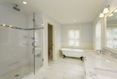 Bright modern bathroom featuring a walk-in glass shower, white clawfoot tub, and double marble sink vanity.