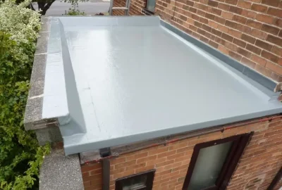 Light grey waterproof membrane coating on a flat roof of a brick building.