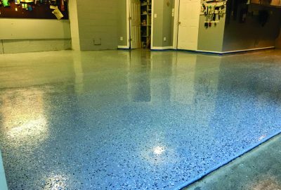 Shiny light blue epoxy garage floor with dark decorative flakes.