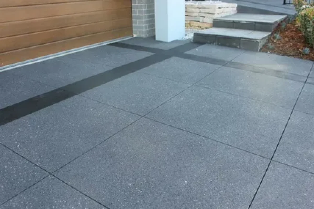 Grey textured concrete driveway with a wide black accent stripe.