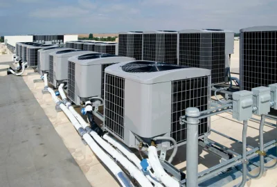 Multiple HVAC units arranged in a row on a building rooftop.
