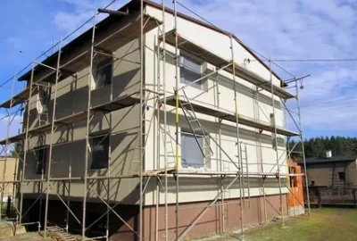 Two-story white building under construction surrounded by metal scaffolding.