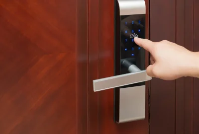 A hand entering a code on an electronic keypad door lock.