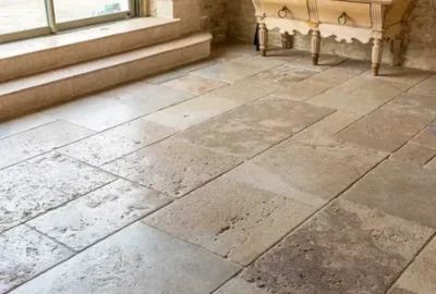 Light-colored natural stone floor tiles in a rustic room with a wooden sideboard and two-step entrance.