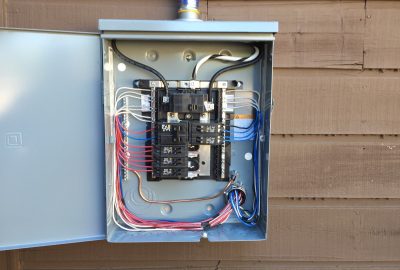 *   Image: An open electrical breaker panel mounted on a brown wooden wall.
    *   Content: The panel contains various circu