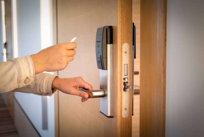 Person using a key card to unlock a wooden door with an electronic lock.