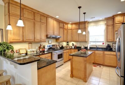 Traditional kitchen with light wood cabinetry, dark granite countertops, a center island, and stainless steel appliances.
