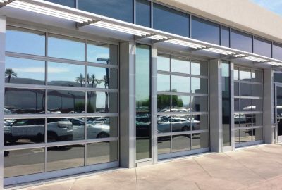 Modern building facade with reflective glass garage doors and a metal awning.