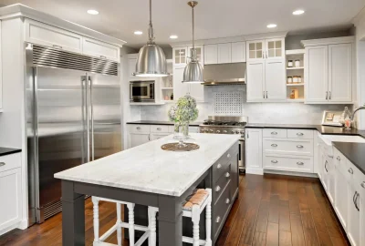 Modern kitchen with white cabinetry, stainless steel appliances, a marble-top island, and dark hardwood floors.