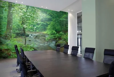 Modern conference room with a long dark table, black chairs, and a large forest river mural on the wall.