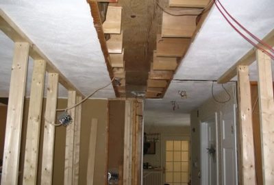 Exposed wooden ceiling joists and wall framing during a home renovation project.