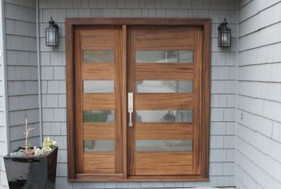 Modern brown wood front door with horizontal frosted glass inserts, flanked by black wall lanterns.