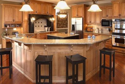Spacious kitchen with light wood cabinetry, granite countertops, and a large island with black bar stools.