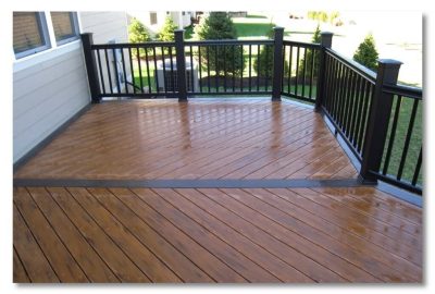 Polished brown wooden deck with black railings and a diagonal plank design.