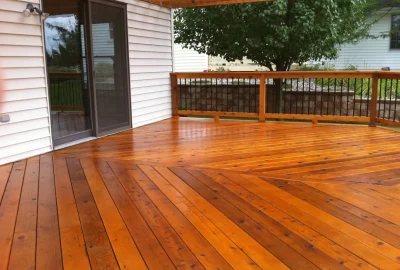 Polished wood deck with a chevron pattern leading to a sliding glass door and wooden railing.