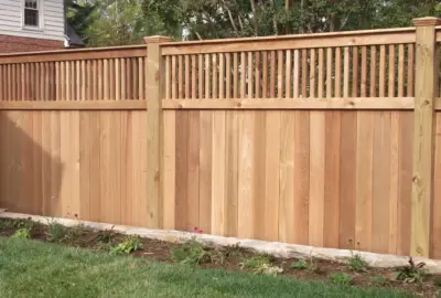 Light wood privacy fence with solid lower panels and a decorative slatted top.