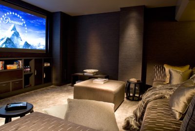 Luxury home theater with a large projection screen displaying the Paramount logo and comfortable plush seating.