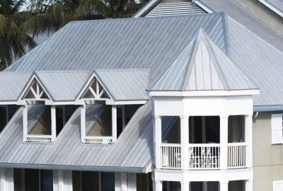 Gray metal roof with white dormer windows and a turret-style balcony.