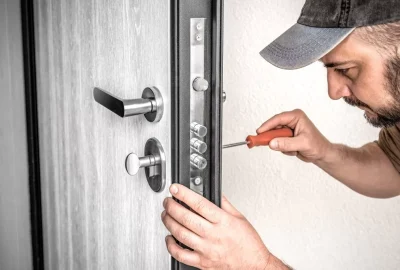 Locksmith repairing a door lock with a screwdriver
