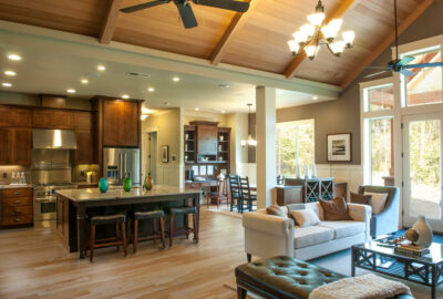 Open-concept living space with a kitchen, dining area, and lounge under a vaulted wood ceiling.