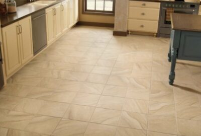 Beige marbled tile flooring in a kitchen with cream cabinets and dark countertops.