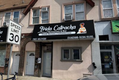 Storefront of Frida Catracha Restaurant & Bar with a black awning advertising Mexican and Central American food.