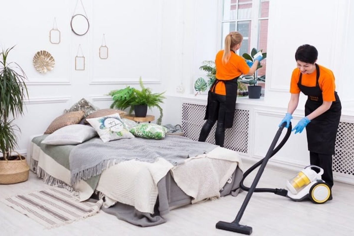 *   Image content: Two professional cleaners in orange shirts and black aprons cleaning a bright, white bedroom.
    *   Pers