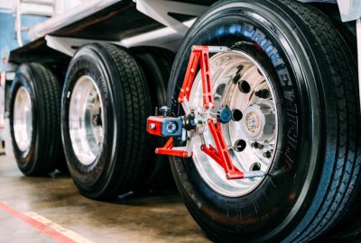 A red and silver alignment tool attached to a large truck tire on a shiny rim.