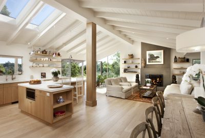Bright open-concept living area with a light wood kitchen, vaulted ceilings with skylights, and a cozy fireplace.